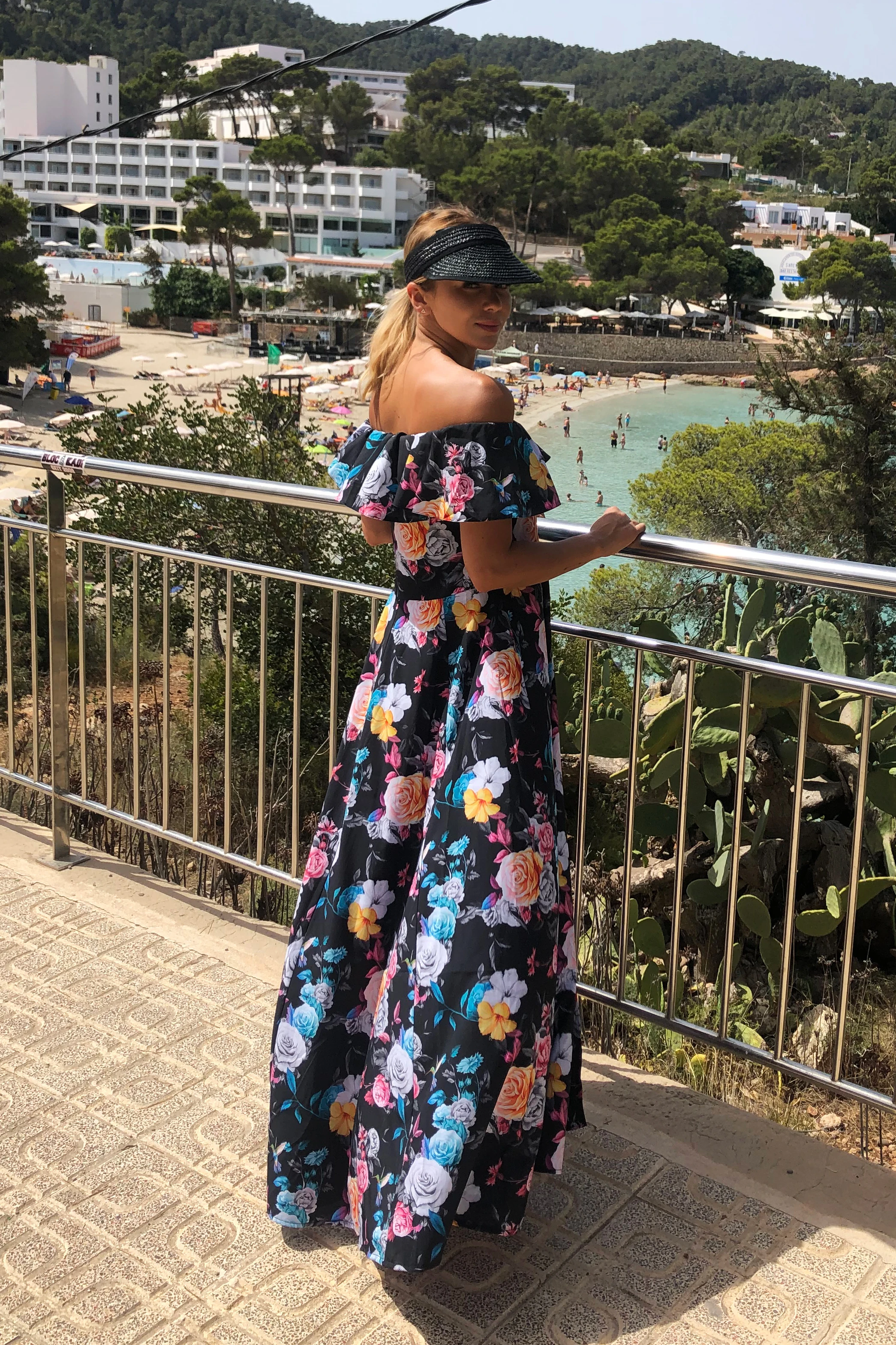 Sukienka maxi w kwiaty, z odkrytymi ramionami, idealna na letnie spacery. Styl boho, lekka i przewiewna, zapewnia komfort i elegancję w ciepłe dni.