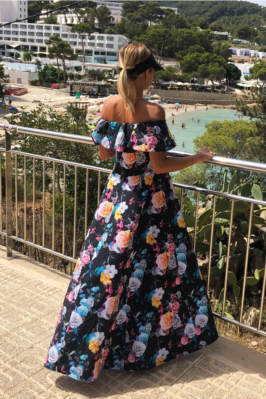 Długa sukienka w kwiaty z odkrytymi ramionami, idealna na letnie spacery. Elegancki krój i kolorowy wzór dodają uroku i kobiecości. Idealna na plażę i wieczorne wyjścia.