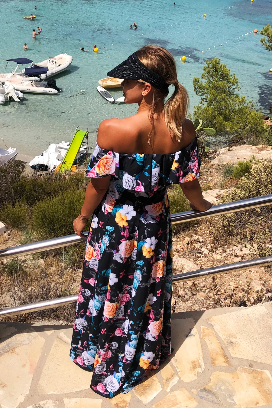 Letnia sukienka maxi w kwiaty, z odkrytymi ramionami, idealna na plażę. Styl boho, lekka i przewiewna, doskonała na wakacyjne spacery. Kolorowy wzór dodaje uroku i świeżości.
