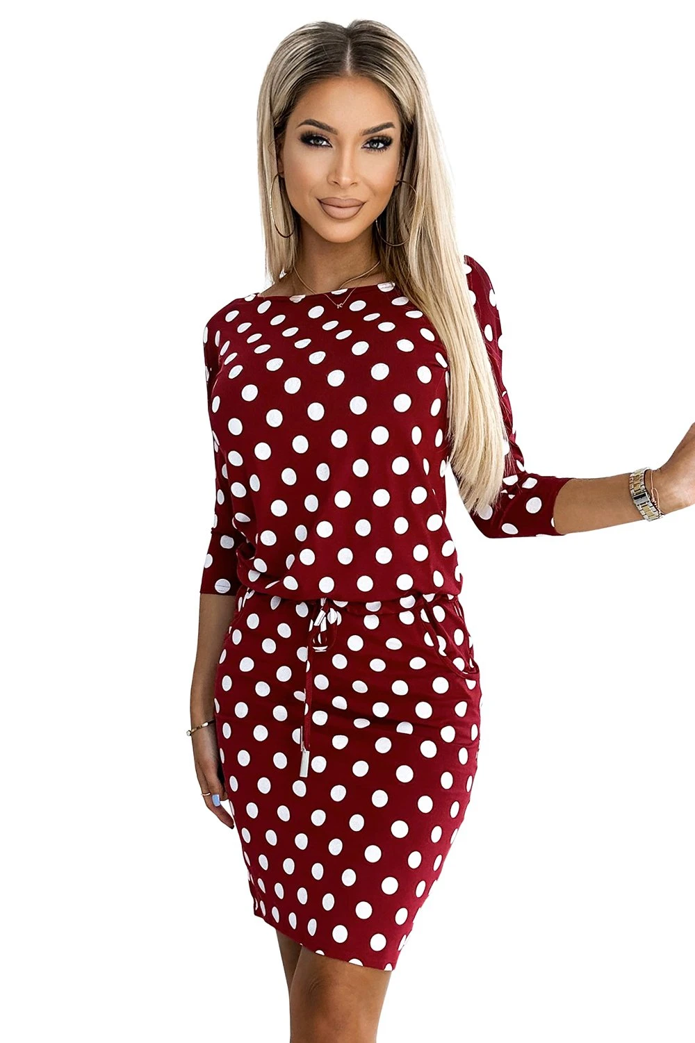 Modelka prezentuje elegancką sukienkę w grochy, która doskonale podkreśla kobiecą sylwetkę. Kobieta na zdjęciu ma na sobie sukienkę w grochy, idealną na każdą okazję, łączącą klasyczny styl z nowoczesnym designem.