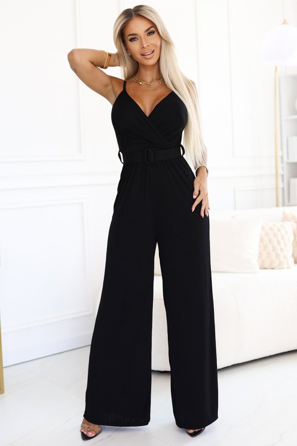 Modelka prezentuje elegancki czarny kombinezon, który idealnie podkreśla sylwetkę i dodaje szyku każdej stylizacji. Kobieta na zdjęciu nosi kombinezon z paskiem, który doskonale akcentuje talię, tworząc harmonijną całość.
