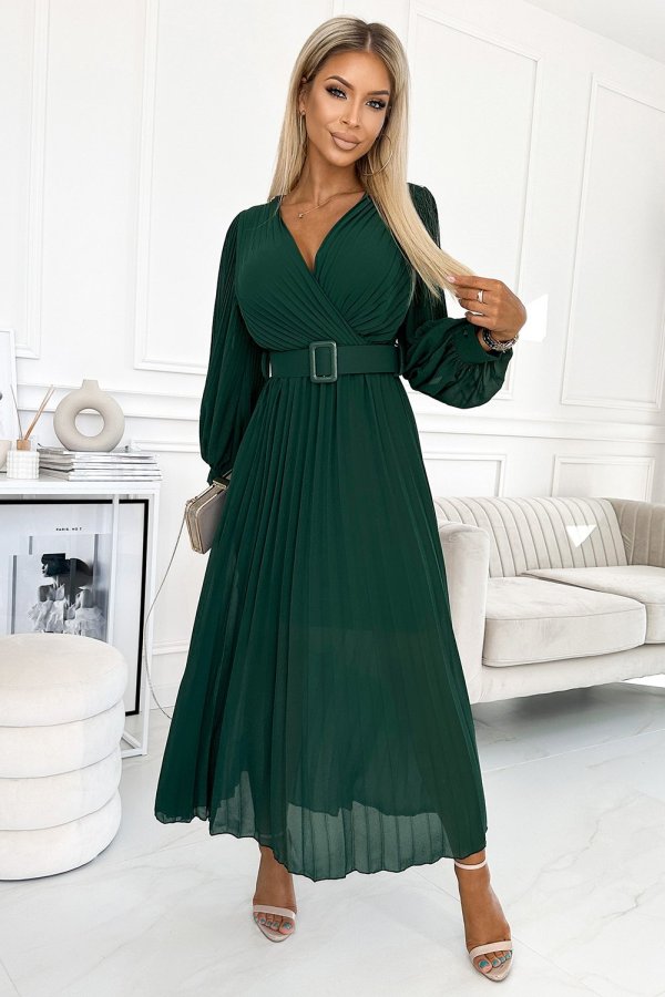 Modelka prezentuje elegancką sukienkę maxi z długim rękawem, która doskonale podkreśla sylwetkę dzięki dopasowanemu paskowi w talii. Kobieta na zdjęciu nosi tę zieloną sukienkę maxi, która idealnie sprawdzi się na wieczorne wyjścia i specjalne okazje.
